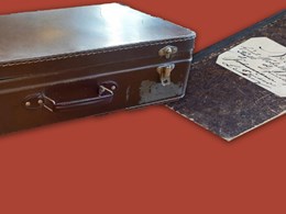 Dekorativt element: En resväska och en gammal nött skrivbok mot röd bakgrund
