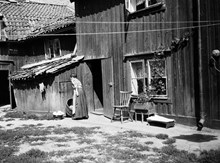 Gårdssidan vid Styrmansgatan 20 (nuvarande 16). En kvinna står bredvid en balja med tvätt och ett träkar