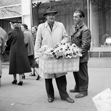 Gatuförsäljare med blommor i en korg