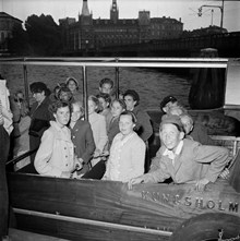 Skånska barn besöker Stockholm. Grupporträtt i en båt. Vy mot Norstedts förlag/Riddarholmen