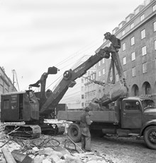 Tunnelbanebygget på Sveavägen. Grävmaskin lastar sten på lastbil.