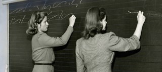 Två kvinnor stenograferar på griffeltavla