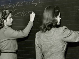 Två kvinnor stenograferar på griffeltavla