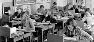 Elever arbetar vid sina bänkar i ett klassrum