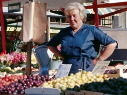 Kvinnlig försäljare vid sitt grönsaksstånd
