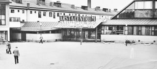 En svartvit bild som föreställer ett torg med människor på.