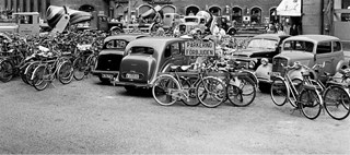 Cyklar uppställda bland bilar framför Konserthuset. 