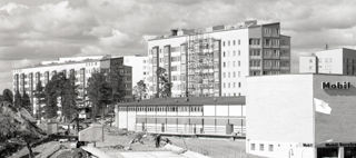 Svart vit bild som föreställer nybyggda hus vid en väg där tunnelbanan kommer byggas.