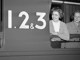 Tre kvinnor tittar ut ur ett fönster på en tågvagn