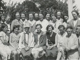 Klassfoto utomhus där kvinnor sitter och står i tre rader och ler mot kameran