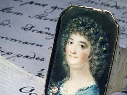 En ring med ett porträtt av Årstafrun ligger ovanpå  ett par pappersark fyllda med text i skrivstil.