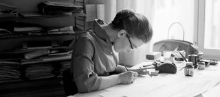 En kvinna sitter böjd över ett skrivbord