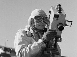 En person med skyddskläder och skyddsglasögon håller i en filmkamera
