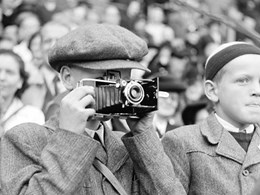 Ett barn håller en kamera framför ansiktet och fotograferar