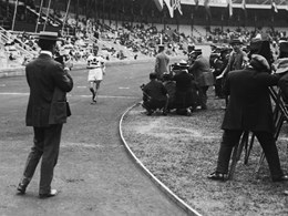 Målgång i 10 000 meter gång. En fotograf står vid mållinjen och en vitklädd löpare är på väg fram på banan inne på Stockholms stadion