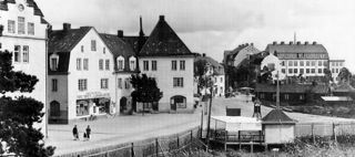 Gammalt foto över Midsommarkransen. Hus, spårvagnsstation och park.