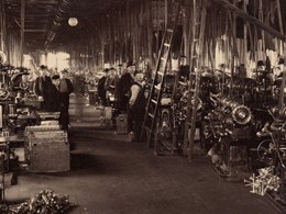 Arbetare står vid maskiner i en fabrikshall