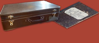 Dekorativt element: En resväska och en gammal nött skrivbok mot röd bakgrund