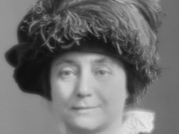Kvinna med hatt med plym tittar in i kameran