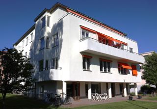 Lågt vitt hus, orangea markiser, pelare