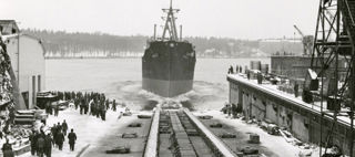 Bilden föreställer ett stort fartyg som åker ut i vattnet efter det legat inne på varvet.