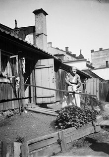 En kvinna står utanför huset på gårdssidan vid Kattgränd 10