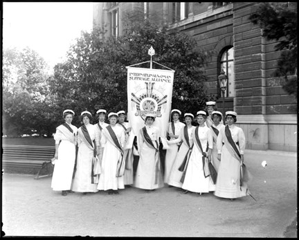 Deltagare i rösträttskongressen 1911 på Södra Blasieholmshamnen med standar där texten lyder "International woman suffrage alliance".