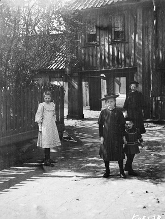 Fyra barn framför trähusbebyggelse.