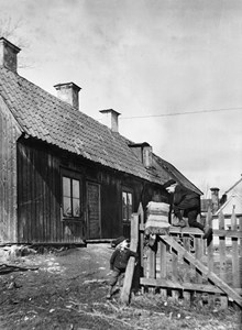 Två pojkar leker på staket vid en träkåk. Huset ligger norr om Vita Berget i kv. Hatten mellan Skånegatan och Bondegatan, senare kv. Kopparn