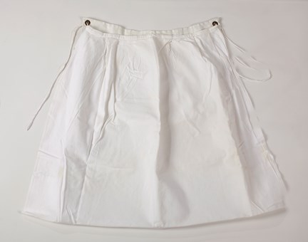 Dubbelt skötförkläde med utsida av vitt tyg och knytband och insida av vävburen plast. 