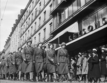 Luftskyddsparad med kvinnor i uniform och hjälmar som marscherar på Sturegatan.