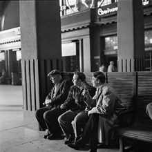 Centralstationen. Stora vänthallen. Tre män sitter på en bänk