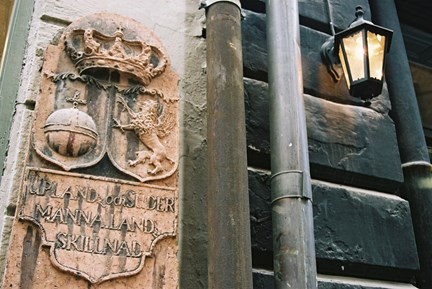 En skylt i sten med en krona, ett riksäpple och ett lejon i relief. Därunder står texten: "Uplandz och Sudermannalandz skillnad".