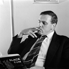 Förlagsredaktör Sven Granat läser en bok och röker en cigarett. Bonniers förlag, Sveavägen 56