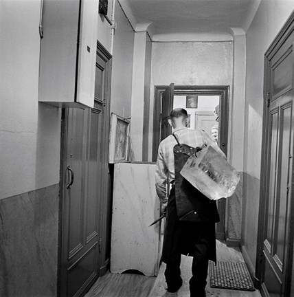 En iskarl kommer med isblock till isskåpet hos fru Björk på Jungfrugatan 13.