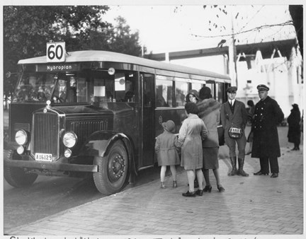 Personer som köar för att kliva på en buss. Bussen står utanför entrén till Stockholmsutställningen 1930.