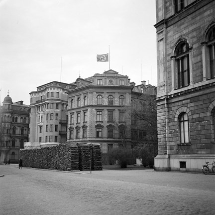 På toppen av ett ståndsmässigt hus från slutet av 1800-talet vajar en flagga med nazisternas svastika på halv stång.