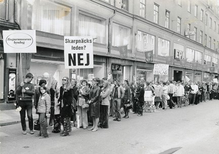 Människor står i ett långt led för att demonstrera mot byggandet av Skarpnäcksleden.