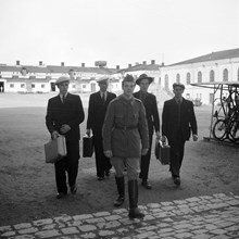 Svea Artilleriregemente. Inryckning. Fyra unga män i civila kläder går bakom en man i uniform