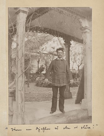 Svartvitt fotografi på August Strindberg som står i en pergola och håller i en fäktningsvärja
