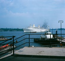Bogserbåten Bill i Franska Bukten och passagerarfartyget Kungsholm för ankar på Strömmen. Vy från Östra Slussgatan