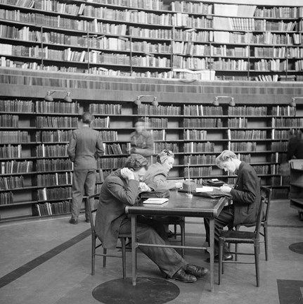 Biblioteksbesökare sitter vid ett bord och läser.