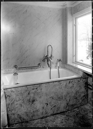 Ett badrum i marmor med inbyggt badkar, dusch och ett stort fönster med utsikt mot naturen.