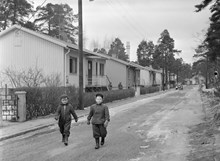 Västberga, Korpmossen. Två barn promenerar i småstugeområde. I bakgrunden LM Erikssons torn