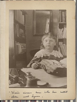 Strindbergs dotter Karin, 6 år, sitter vid pappas skrivbord och tittar i en bok