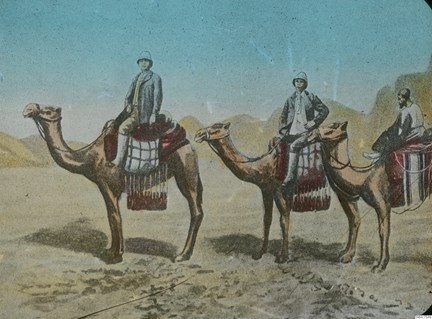 Tre män på kameler med berg i bakgrunden.