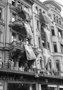 Stureplan 6,  nuvarande Stureplan 2. Folk står i fönster, på balkonger och på restaurang Sturehofs tak i samband med firandet av kung Gustaf V:s 90-årsdag