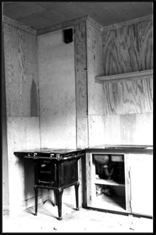 Interiör med plywoodbeklädnad i kök samt gasspis och diskbänk i hus i Enskede småstugeområde