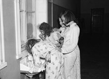 Skolbarn från landsbygden besöker Stockholm. Fyra flickor borstar tänderna iklädda pyjamas