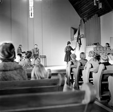 Scoutceremoni i Missionskyrkan i Enskede. Ledare med en pojke. T.h. en flicka med fana